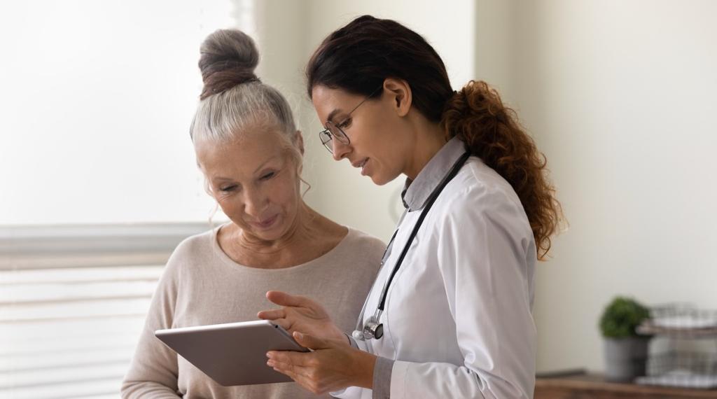 Serious GP doctor showing tablet screen to female patient