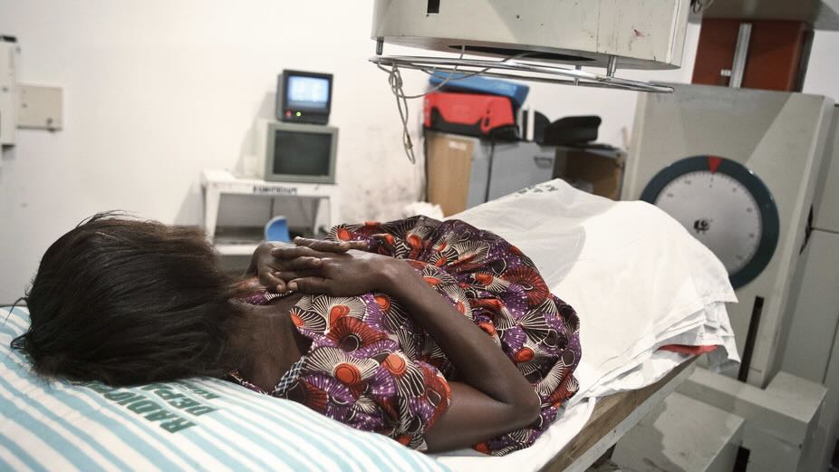 A 52-year-old woman with bladder cancer lies under a radiotherapy simulator used to pinpoint areas to treat at the Korle Bu Teaching Hospital​ in Ghana